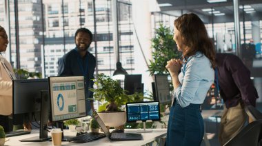 Çok ırklı iş arkadaşları başarıyı kutluyor, heyecanlarını dile getiriyor, beşlik çakıyor. Çok ırklı iş arkadaşları iş başarısından memnunlar, birbirlerini tebrik ediyorlar, kamera A.