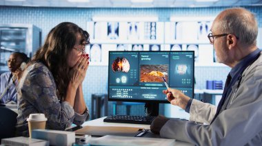 Hekim, bir hastaya MRI taraması için danışarak tümör büyümesi ve modern bir sağlık ofisindeki potansiyel kemoterapi seçenekleri hakkında bilgi veriyor. Tavsiyeler. Kamera A.