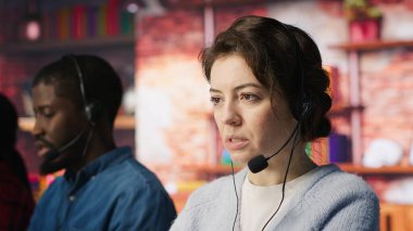 Ofiste müşterilere yardımcı olmak için kulaklık takan çağrı merkezi çalışanları. Müşteri desteği veren işçiler, telefon görüşmesinde müşterilerle iletişim kuran, hizmet sağlayan, kamera A)