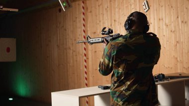 Taktik operasyon teçhizatı kullanan, saldırı tüfeği kullanan mutlu askerlerin portresi. Atış poligonunda gülümseyen adam göreve hazırlanıyor, yarı otomatik silahla pratik yapıyor, kamera A