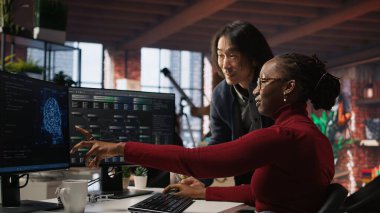 Yapay zeka girişiminde neşeli bir yönetici işçi kodlama uygulamalarıyla gülüyor. Mutlu takım lideri çalışanıyla şakalaşıyor rahat çalışma alanında kod testi yapıyor, kamera A