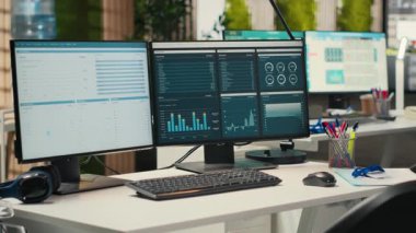Boş şirket ofisinde yüksek teknoloji ve çift monitörler, iş stratejisi ve rapor yazma için hazır analitik araçlar bulunuyor. Profesyonel büyüme ve örgütsel başarı.