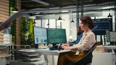 Genç iş kadını, ofisteki görevleri çözerken, içgörüleri veya KPI ölçümlerini izlerken bir podcast 'e odaklandı. Dijital araçlarla genişleme planları için strateji raporları. Kamera A.