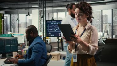 Yeni bir vizyon oluşturmak için dijital araçlar kullanan kadın ofis yöneticisi, modern ofis ortamında hedeflere ulaşmak için tabletteki performans veri içgörülerini gözden geçiriyor. Kamera A.