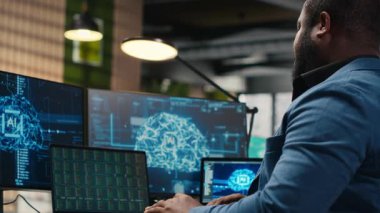 Siyah işadamı yapay zeka dijital araçları ve makine öğrenme modelleri kullanarak, yenilik için veri analizi yaparak uyarlanabilir optimize iş çözümleri yaratıyor. Bulut hesaplama. Kamera B.