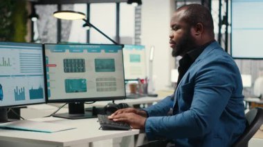 Siyahi erkek analist, dijital araçlarla bilişim şirketinin gelişimine, analizlere ve iş yerindeki performans ölçümlerine odaklandı. Personel planlama çözümleri ve hedefleri hizalamak. Kamera B.