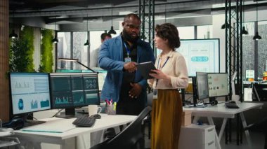 Çeşitli işçiler büyüme stratejisini geliştirmek için dijital araçlar ve analizler kullanırken, modern ofis ortamında yenilik ve kalkınmayı teşvik etmek için tablet üzerindeki mali görüşleri gözden geçiriyorlar. Kamera A.