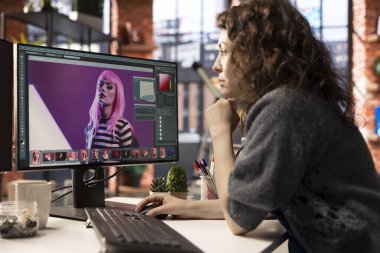 Ajans ofisindeki modern bir bilgisayar kurulumunda geliştirme tekniği kullanan kadın grafik tasarımcısı fotoğrafları düzenliyor. Dijital tasarım profesyoneli ve fotoğrafçılığı için ideal çalışma alanı.