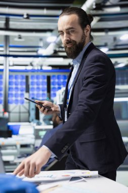 Giysi içindeki profesyonel enerji analisti güneş paneli teşhislerini inceleyerek, fotovoltaik yenilenebilir enerji alanındaki endüstriyel uzmanlık ve iş zekasının entegrasyonunu vurguluyor.