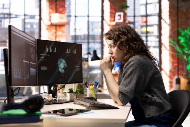 Uzaktan kumandalı işçi iş konferansını PC monitöründen izliyor, not defterine bilgi yazıyor. Ofisteki serbest çalışan bilgisayardaki sunum grafiklerine bakıyor, notlar alıyor..