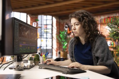 Yaratıcı ajans ofisinde video prodüksiyonunda çalışan genç film yapımcısı kadın video klipleri karıştırıyor ve montajı yapıyor. Yaratıcı süreçte film düzenleme yazılımı, film endüstrisi.