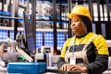 Otomatik fabrika mühendisi dijital arayüz kullanarak üretim hattını analiz ediyor. Akıllı üretim sistemi verimlilik için robotik silahlar, taşıma bantları ve endüstriyel otomasyona sahiptir..