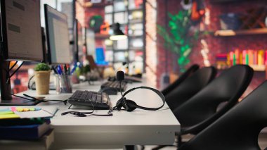 Müşteri merkezinin çalışma alanında kullanılan ses ekipmanı iletişim cihazları, yakın çekim. Çağrı merkezinde mikrofonlu kulaklıklar masanın yanındaki klavyenin yanında.