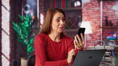 Olgun, neşeli bir kadın telefonuyla video konferansına katılıyor. Önemli sanal dersler için öğretmeniyle buluşuyor. Akıllı telefondan yüksek lisans derecesi almak için çok çalışan biri. Kamera A.