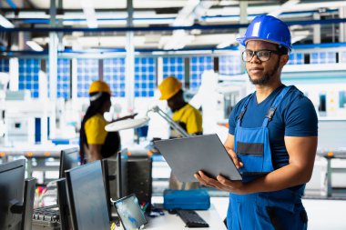 Güneş enerjisi mühendisi, araştırma ve yenilik odaklı çevre dostu fabrikada tasarım modellerini güncelliyor. Erkek teknisyen dijital sistemler kullanarak sürdürülebilir endüstriyel büyümeyi destekliyor.