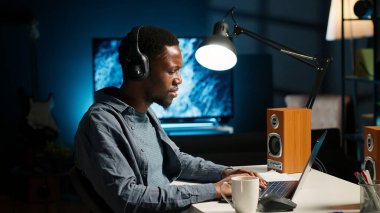 Afrikalı Amerikalı bir adam iş arkadaşlarıyla merkez büroda video konferansı yapıyor. Genç erkek serbest çalışan internetten iş birliği yapıyor ve bilgisayarında görevleri tartışıyor, görüntülü konuşma. Kamera B.