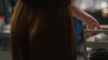 Sekreterin evrak ve arşivlenmiş dosyalarla dolu bir yük arabasını iterken, bir meslektaşına doküman götürürken ve verimli kaynak dağıtımını sağlarken. Üretim görevleri. Kamera B.