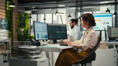 Üst düzey bir ofiste çalışan, performans ölçümlerini ve iş stratejisini bilgisayar monitörüne analiz eden, rapor yazma ve sonuç ve başarı odaklı kadın çalışan. Kamera A.