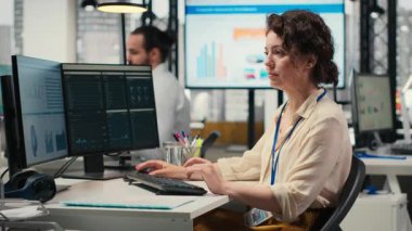 Üst düzey bir ofiste çalışan, performans ölçümlerini ve iş stratejisini bilgisayar monitörüne analiz eden, rapor yazma ve sonuç ve başarı odaklı kadın çalışan. Kamera B.