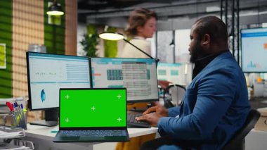 Siyahi analist dizüstü bilgisayardaki kroma tuşlu grafikleri analiz etmek, iş yönetimi verimliliğini artırmak ve kalkınma hedeflerine ulaşmak için strateji raporları hazırlamak için bilgisayar kullanıyor. Kamera A.