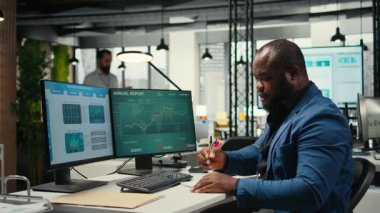 Siyahi iş danışmanı, yeni bir strateji oluşturmak ve modern bir ofiste proje hedeflerini gerçekleştirmek için notlar alıyor ve küresel genişlemeyi tahmin etmek için bazı veri içgörüleri yazıyor. Verimlilik motivasyonu