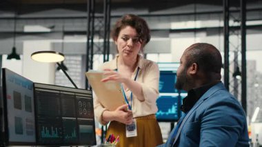 Aylık raporları tamamlamada birbirlerine danışan çok ırklı çalışma ekibi, KPI 'nin iş verimliliği hakkındaki veri içgörülerini gözden geçiriyor. Başarı için çalışanlar arası işbirliği. Kamera B.