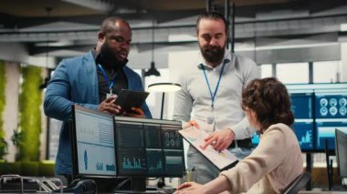 Aylık raporları tamamlamada birbirlerine danışan çok ırklı çalışma ekibi, KPI 'nin iş verimliliği hakkındaki veri içgörülerini gözden geçiriyor. Başarı için çalışanlar arası işbirliği. Kamera B.