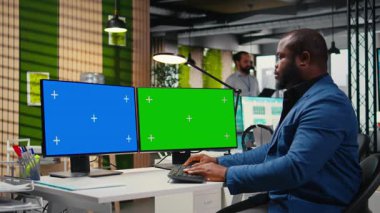 Afrika kökenli Amerikalı işadamı, küresel kalkınma için yeni bir iş stratejisi oluşturan, izole edilmiş çift monitörlü raporları inceliyor. Hedefler verimlilikle aynı hizada. Kamera A.