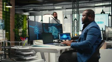 Siyahi adam IT uzmanı veri tahmini için nöral ağ sistemlerini ele alır, yapay zeka otomasyon araçlarını dijitalleştirme ile birleştirerek çok uluslu şirketlerin verimliliğini ve yeniliğini sağlar. Kamera A.