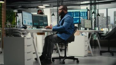 Afrika kökenli Amerikalı erkek, finansal veri tahminlerini bilgisayarda analiz ediyor. Şirket amaçlarıyla uyum sağlamak için yenilikçi iş çözümleri geliştiriyor. Profesyonel çevre. Kamera A.