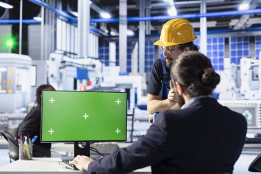 Güneş panelleri fabrika personeli yüksek verimliliği sağlamak için izole ekran bilgisayarı kullanarak kalite kontrolü yapar. Photovoltaics fabrikasındaki iş arkadaşları montaj hatlarını kalibre ediyorlar kroma anahtarındaki robotik kollar