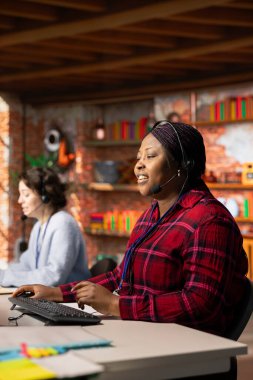 Gülümseyen çağrı merkezi çalışanı müşteri geribildirim verilerini analiz eder, şikayetleri azaltmak için çalışır. Neşeli Afro-Amerikan müşteri hizmetleri çalışanı müşteri ihtiyaçlarını gidermek için problem çözme becerilerini kullanıyor