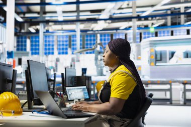 Güneş paneli fabrika mühendisi dizüstü bilgisayardaki alternatif enerji sistemleri için CAD modelleri ve teknik çizimler tasarlıyor. Kadın işçiler verimlilik ve yenilik için fotovoltaik tasarımı sağlıyorlar.