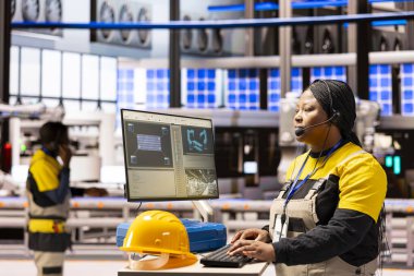 Endüstriyel otomasyon sistemini denetleyen ve üretim hattını geliştiren kadın mühendis. Kulaklıklı siyahi kadın Endüstri 4.0 yazılım gereksinimleri ve akıllı fabrika optimizasyonunu yönetiyor..