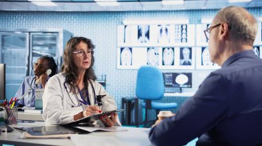 Sigortası olan eski bir hastanın röntgen taramalarını inceleyen uzman bir doktor, yaşlı bir hastayla sağlığın korunması ve önlenmesi konusunu tartışıyor. Profesyonel tavsiye. Kamera B.