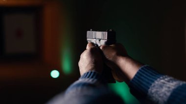 Atış poligonu müşterisi tabancayla ateş ediyor. Hedefe ateş edip etmediğini kontrol ediyor. Atış poligonunda silah kullanmayı öğrenen, hedeflerin görüntülerini analiz eden, kamera B