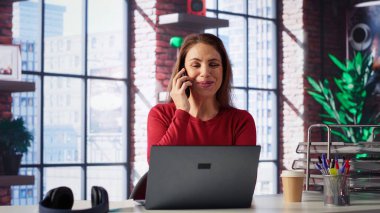 Modern bir çatı katında profesyonel bir kadın masasından bir telefon alıyor. Dizüstü bilgisayarıyla birden fazla iş yapıyor, iş stratejileri, serbest çalışma ve kariyer planlama konularını tartışıyor. Verimlilik. Kamera A.