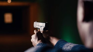 Atış poligonu müşterileri silah dolduruyor, eğlence amaçlı spor faaliyetleri sırasında hedefleri vurmaya hazırlanıyor. Atış menzilindeki adam, tabancayı cephaneyle dolduruyor. Kamera B, kapat.