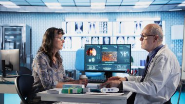 Doktor ve hasta önleyici tıp ve kanser farkındalığı stratejileri üzerine odaklanan bir röntgen ve MRI taraması hakkında tartıştılar. Bir kadını kemoterapi seçenekleri ve önleyici bakım konusunda eğitmek. Kamera A.