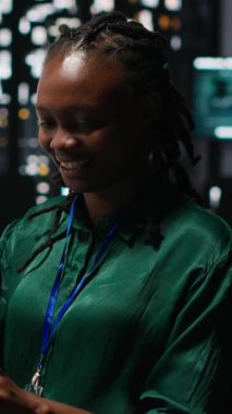 Gülümseyen siyah analistin dikey video portresi önemli bir toplantıya hazırlanıyor, saatler sonra kalkınma fonlarını artırıyor. İş arkadaşları hedef belirleme tartışmasına katıldı