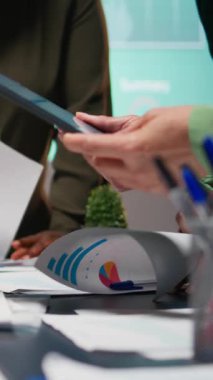 Çok ırklı grupların bir strateji odasında toplanıp, proje geliştirme, üretkenlik için görsel verileri, istatistikleri ve risk değerlendirme dosyalarını analiz ettiği dikey videodan sonra. Kamera A.