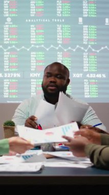 Şirketin hedeflerini yatırımcıların şirket ilerlemesi beklentileriyle aynı hizaya getirmek için projeksiyon ve diyagramlar kullanarak dosyaları ve performans göstergelerini değerlendiren dikey Video Çeşitli profesyoneller grubu