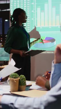 İş dünyasının analistlerinden oluşan dikey video ekibi, iş hedeflerine ulaşmak, bütçe ve kaynak tahsisi sağlamak amacıyla proje detayları ve tahminleri hakkında bilgi alışverişinde bulunuyor. Yönetim ekibi gece toplantısında.