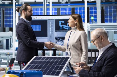 Güneş panelleri fabrika işadamı yatırımcıyla tokalaşıyor ve yatırımı değerlendirmek üzere tesise gelişini memnuniyetle karşılıyor. Fotovoltaik fabrikası yöneticileri üretim sürecini analiz etmek ve el sıkışmak için toplanıyor.