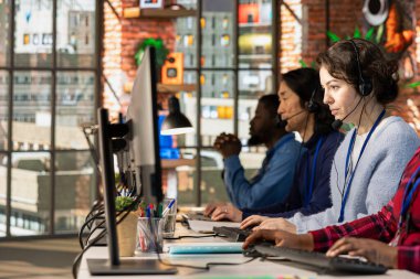 Çok ırklı çağrı merkezi çalışanlarından oluşan bir ekip üzgün müşterilerle ilgileniyor, ofis masasında kulaklıkla konuşuyorlar. İş yerinde müşteri destekleme işi yapan çok ırklı meslektaşlar, müşteri şikâyetleriyle ilgileniyorlar