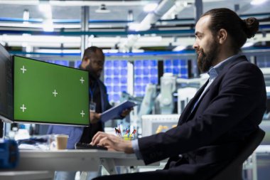 Kalite kontrol uzmanı, güneş enerjisi santralinin masasında çalışan üretim sürecini fotokopi alanı görüntüsüyle gözden geçiriyor. Erkek profesyonel, kusursuz imalat faaliyeti sağlıyor..