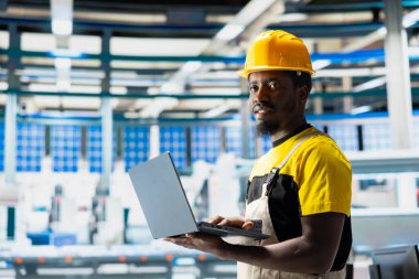 Fotovoltaik fabrikasındaki insan mühendisi arızalı sistemleri tespit etmek için bilgisayarda izleme yazılımı kullanıyor. Güneş panelleri fabrika işçisi üretimini azaltıyor, üretimi azaltıyor..