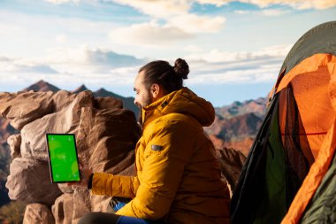 Genç gezgin, krom anahtarın yanındaki yüksek rakımlı yabanı, temiz hava ve manzaralı dağ manzarasının yürüyüş ve macera için ilham verici bir ortam sağladığı bir cihaz kullanarak kucaklıyor..