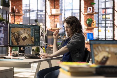 Tasarım ajansındaki kadın çalışan mimari yazılımla bir dairenin 3 boyutlu görüntüsünü oluşturuyor. Mobilyaların ve döşemelerin kişiselleştirilmesine izin vermek için bilgisayar destekli araçlar kullanır.