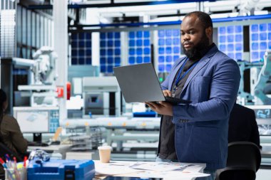 Bir güneş paneli tesisinde performans verilerini kontrol eden operasyon çalışanı, işyeri verimliliğine olan bağlılığını gösteriyor ve yeşil enerji imalatı ve mühendisliği üzerinde çalışıyor.